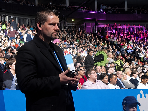 Professional event security guard standing alert in front of a massive stadium crowd