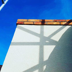 Union flag shadow on white rendered wall with brick coping under a clear blue sky