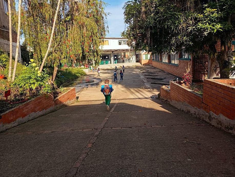 Niño con mochila caminando por el patio de un colegio