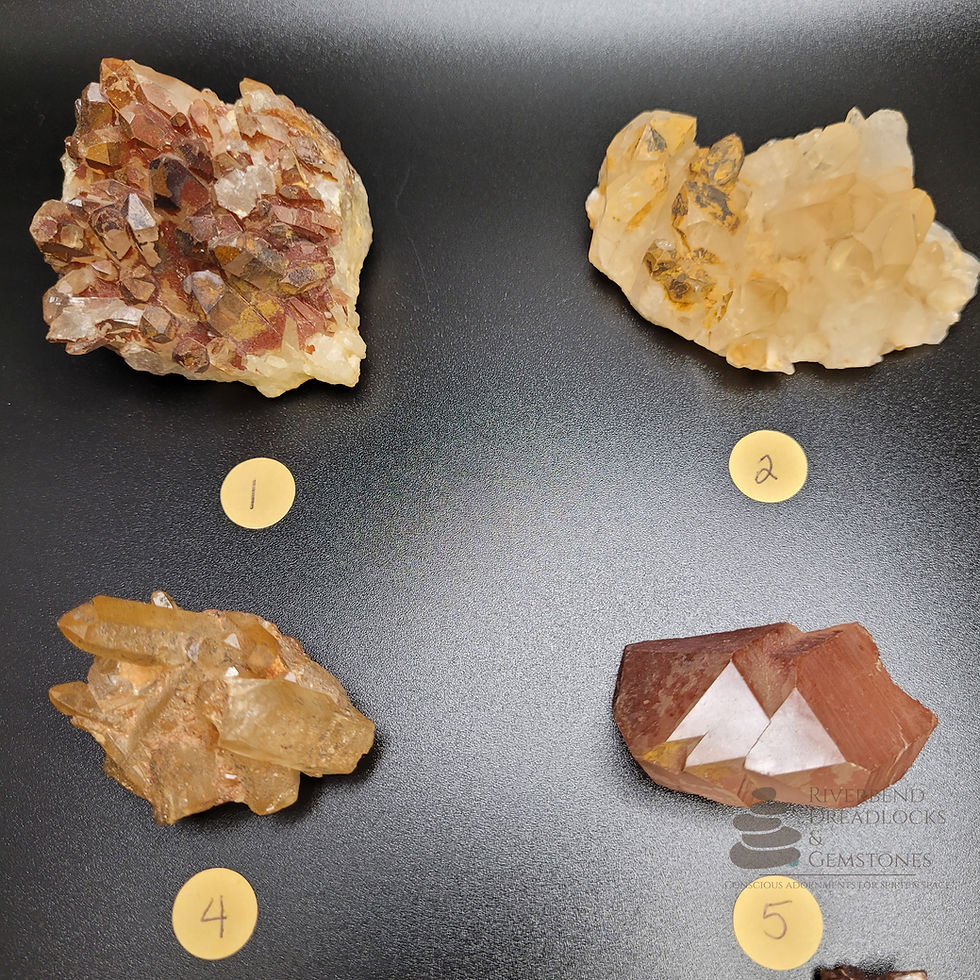 Thumbnail: Close up of several Hematoid Quartz Raw crystal clusters and points, ranging from 1.0 to 2.5 inches. They are lying on a black background, each labeled by a small round Kraft paper sticker and a corresponding letter.