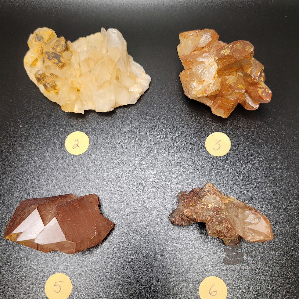 Thumbnail: Close up of several Hematoid Quartz Raw crystal clusters and points, ranging from 1.0 to 2.5 inches. They are lying on a black background, each labeled by a small round Kraft paper sticker and a corresponding letter.