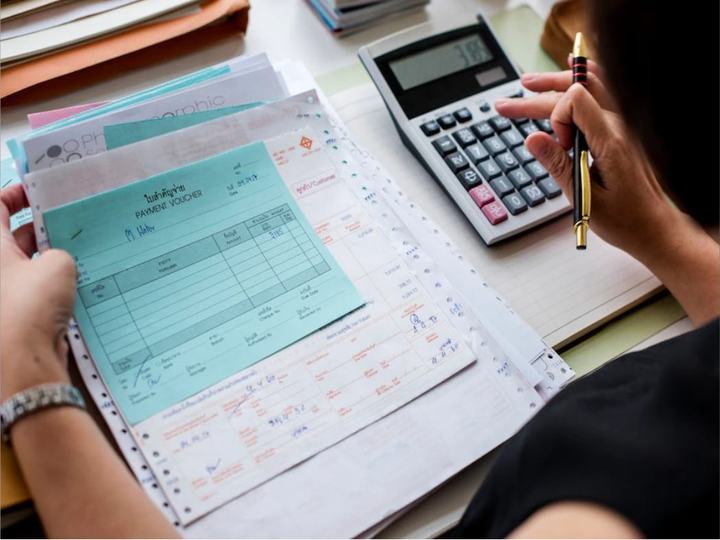 Pessoa conferindo holerites com uma calculadora