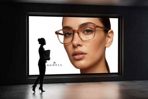 Painel Agnell em galeria com mulher usando óculos marrom e silhueta feminina ao fundo