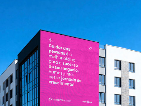 Fachada de prédio com painel pink Armonias e texto "Cuidar das pessoas é o melhor atalho para o sucesso do seu negócio"