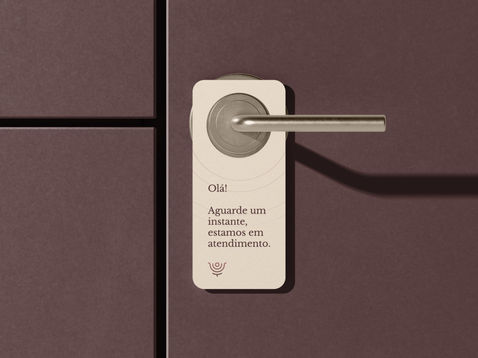 Aviso de fechadura consultório Camila M. Santos em vinho com texto "Olá! Aguarde um instante, estamos em atendimento"