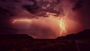a dark storm with bright lightning against a desert backdrop