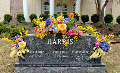 Colorful cemetery flower arrangements displayed on family headstone in Springdale Arkansas
