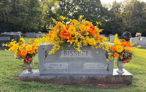 Pink cemetery flower arrangement placed beside headstone for graveside tribute