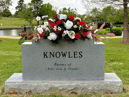 Symmetrical red white and green cemetery flower arrangement on double headstone in Rogers Arkansas cemetery