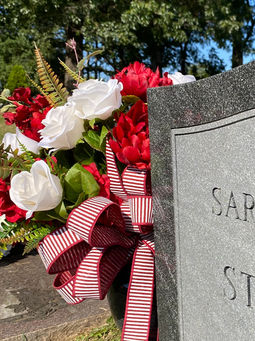 Red white and blue cemetery flower arrangement on upright headstone in Fayetteville Arkansas cemetery placed at St. Joseph Catholic Cemetery, Fayetteville, Arkansas.