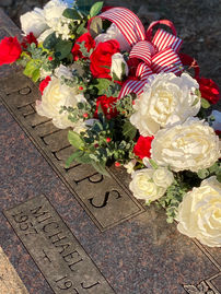 Full length cemetery flower arrangement across granite headstone for graveside memorial display