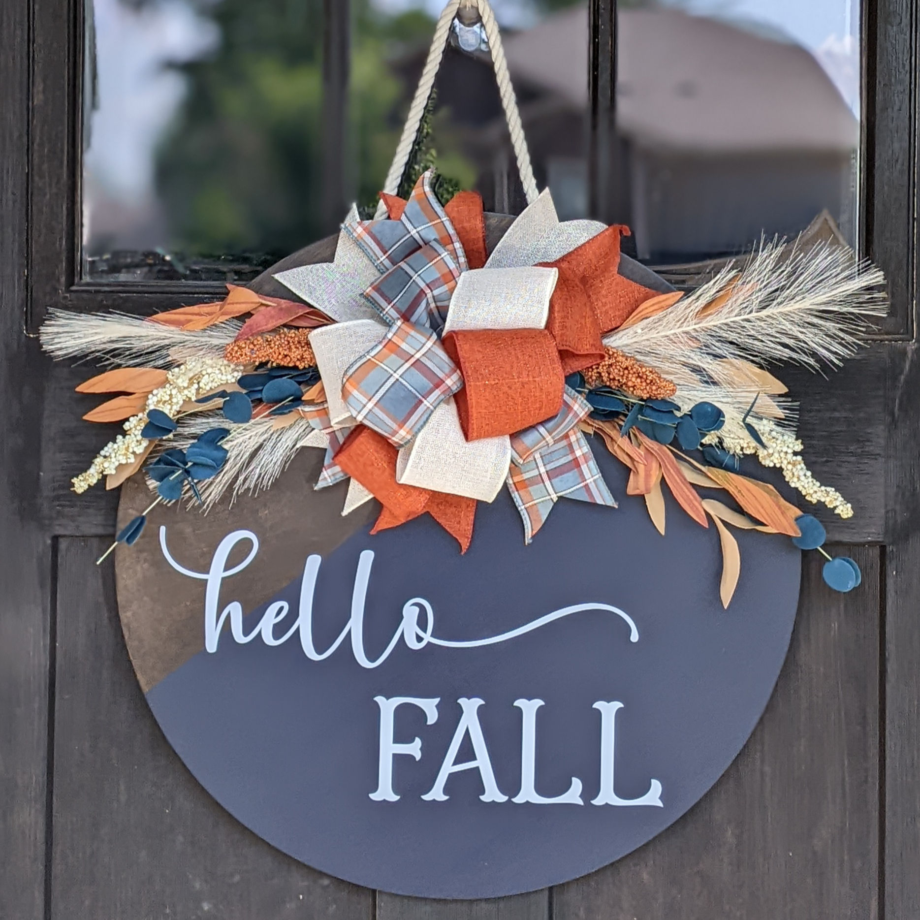 dark blue round door hanger that says hello fall and has fall greenery and a bow at the top