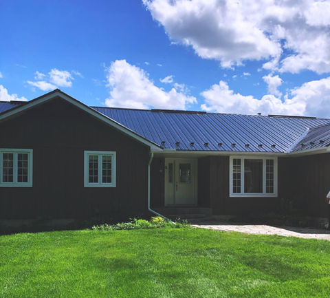 Ranch-style house with dark gray standing seam metal roof and white trim.