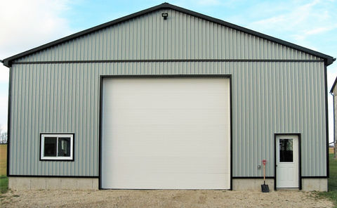 Light gray steel building with white overhead door and metal siding.