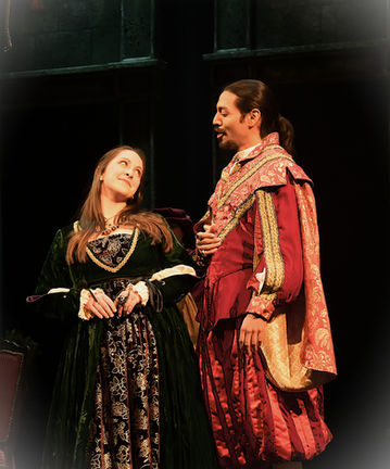 Victoria wears a green velvet gown onstage as Countess Ceprano. She gives an approving look to a male performer dressed in red and gold regal attire.