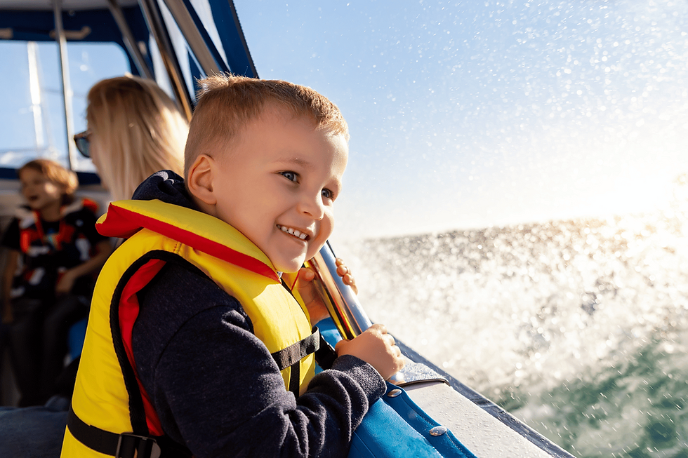 Small smiling child in a life jacket inside a boat enjoying the ride.