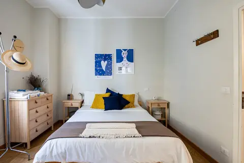 Camera da letto accogliente e stilosa in un appartamento vacanze a Monteverde, Roma, con cuscini colorati e decorazioni artistiche.