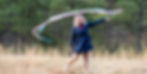 Amanda Surratt in a blue dress standing in a field waving ribbons in the air
