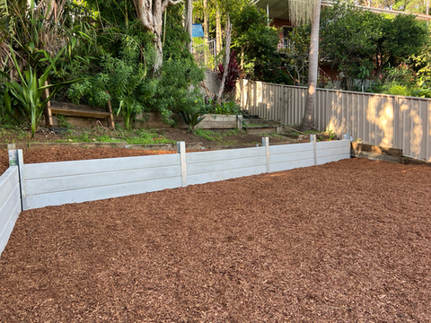 Concrete sleeper retaining wall in a backyard with mulch.