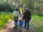 two adults holding hands with a child walking on path