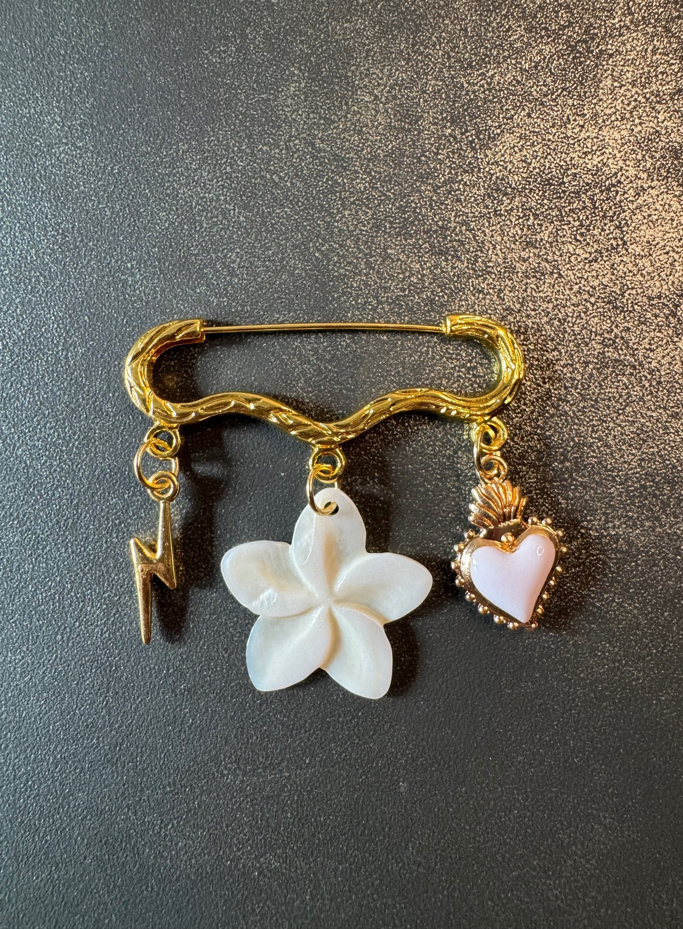 Broche dorée en acier inoxydable avec une fleur nacrée, un éclair et un coeur sacré dans les tons de blanc
