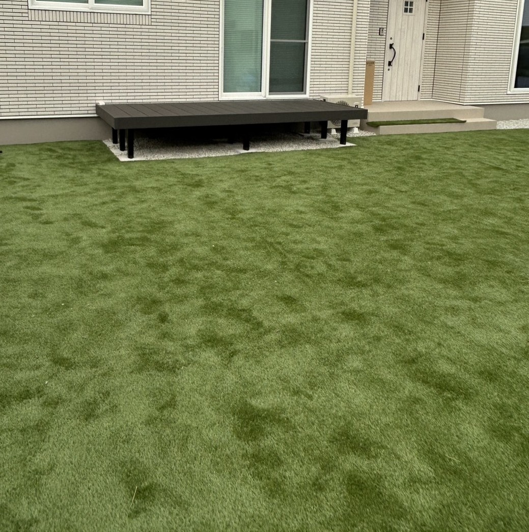 デッキの前に人工芝が広がる住宅の庭