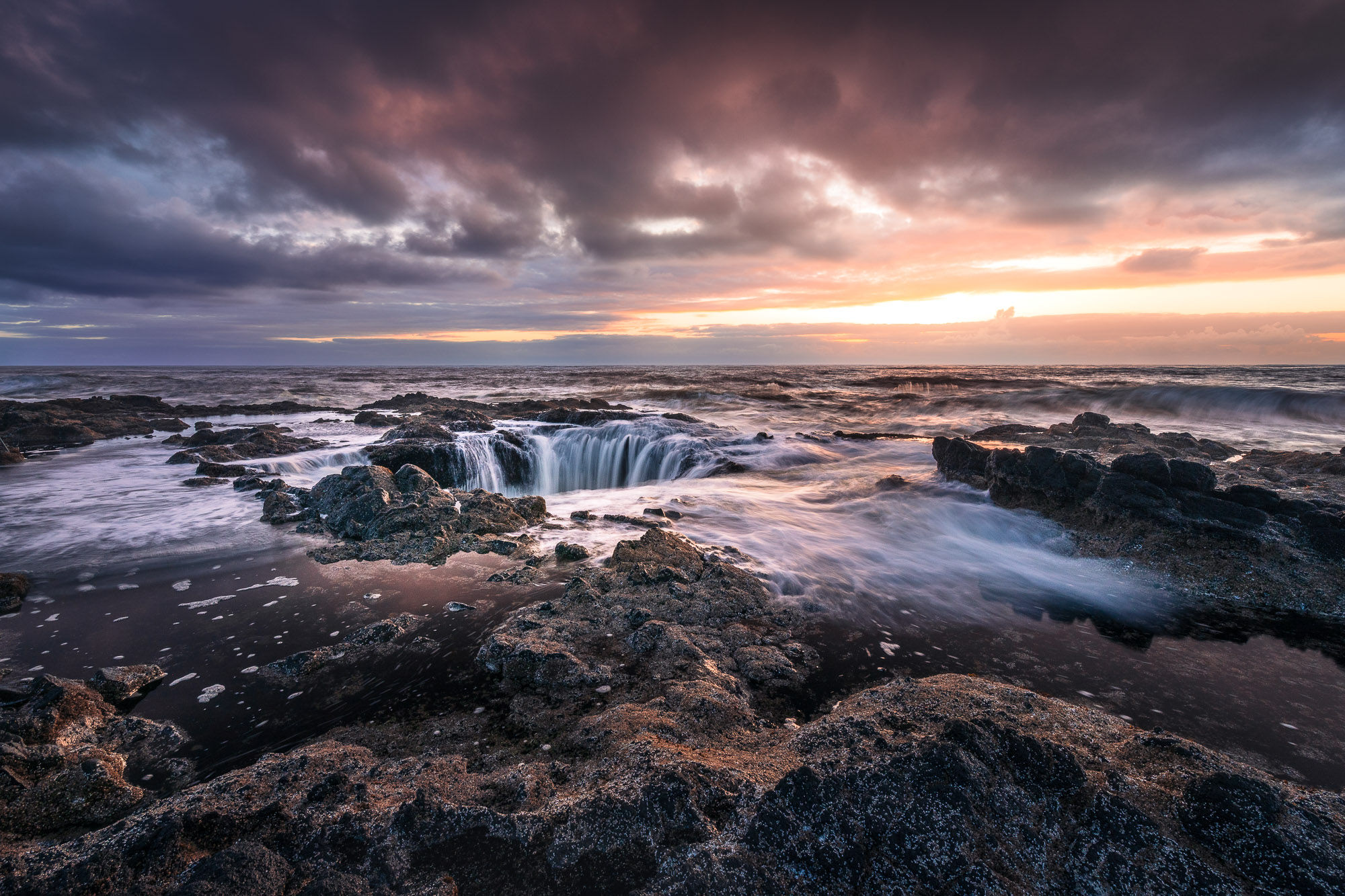 Sunset casts a dramatic light over the rocky coastline, highlighting the swirling waters of Thor's Well. By Michael Rung