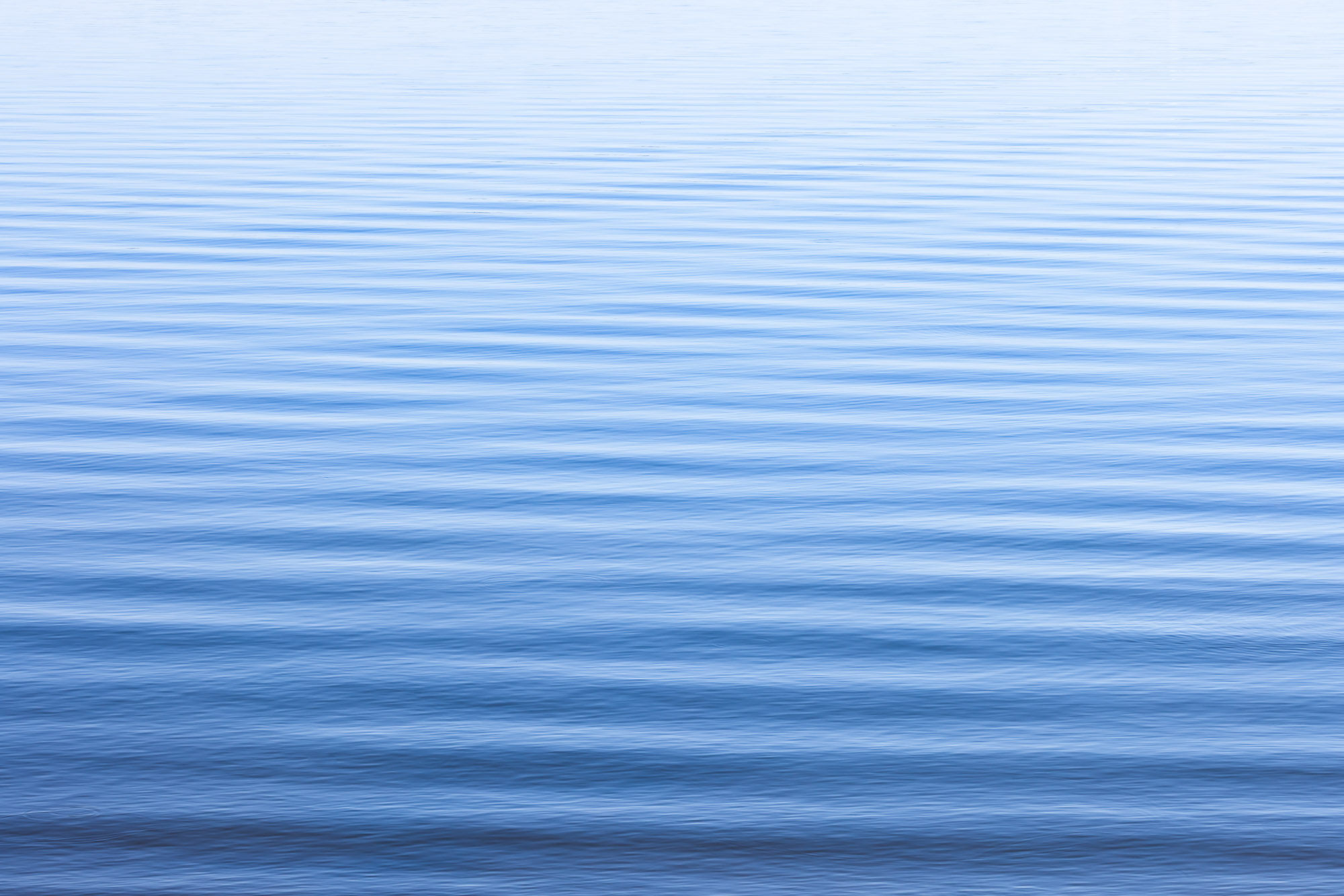 Serene rippling waves at Eagle Mountain Park in north Texas, showcasing water reflecting the blue sky. By Michael Rung