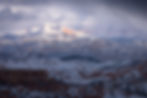 Sunlight burning through a winter storm onto a mountain landscape beyond Bryce Canyon National Park
