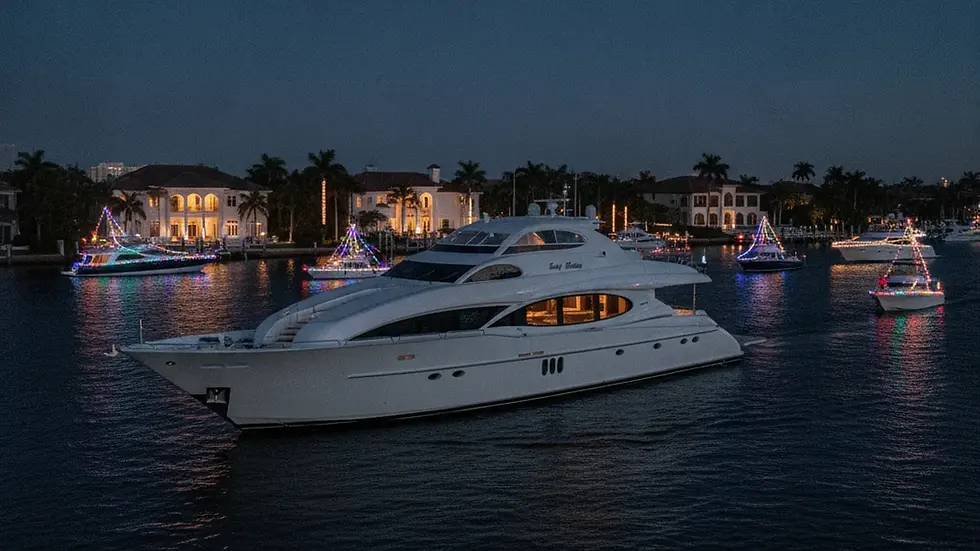 Guests on the deck of a yacht watching lit boats pass on the water at night