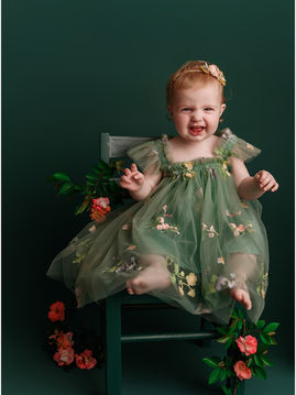 One year old in flower dress on green chair