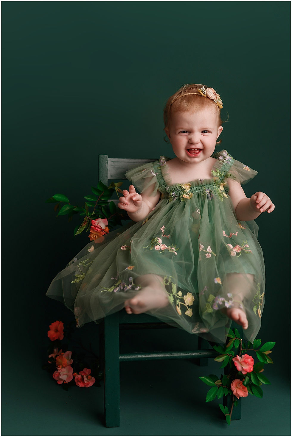 One year old in flower dress on green chair