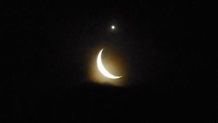 Lunedì 18 maggio 2026, dopo settimane di congiunzioni mattutine difficili da osservare, finalmente arriva un appuntamento serale facilmente accessibile. Una sottile falce di Luna crescente, di circa due-tre giorni, tramonterà a ovest accompagnata dal pianeta più luminoso del cielo dopo Sole e Luna: Venere. L'osservazione è prevista intorno alle 21:30, quando il cielo è ancora abbastanza chiaro per cogliere il contrasto tra il blu del crepuscolo e le due luci.
