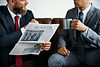 Two people having a discussion over coffee and a newspaper