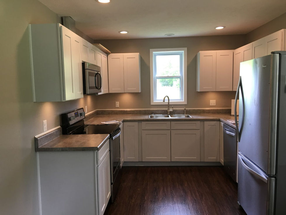 Newly renovated kitchen with new wood flooring, new cabinets, new countertops, new window, and new stove and fridge. Work provided by The Plantation Room Company.