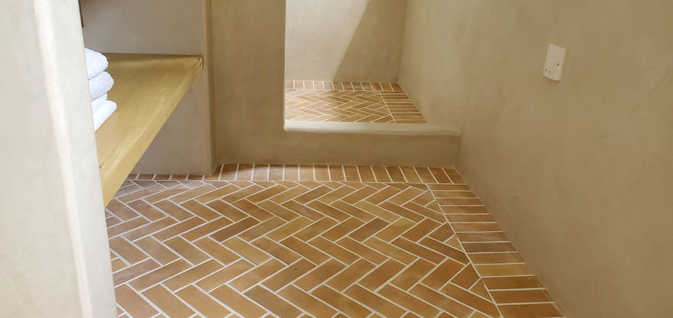 Gros plan sur la faïence type bejmat, pose en chevrons avec frise, douche et plan vasque maçonnés en béton ciré