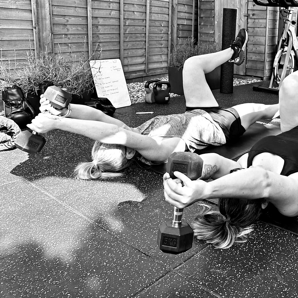 Two women doing fitness strength personal training with dumbbells