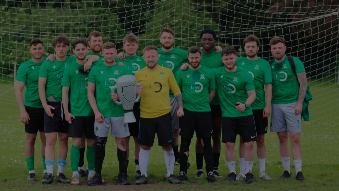 An image of a Sunday League football squad standing in front of a football net, holding up an inflatable trophy.