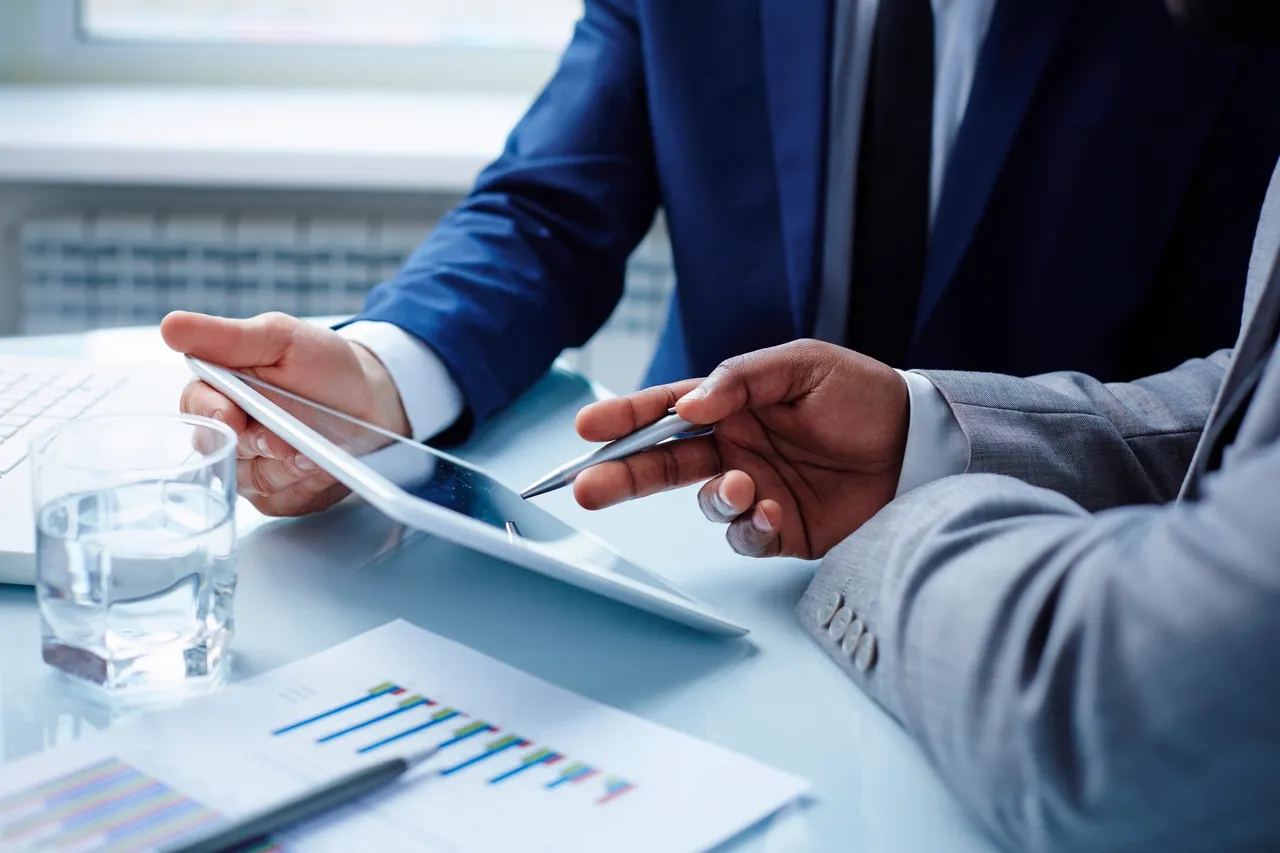two businessmen discussing info on a tablet