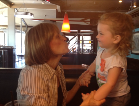a woman blowing a kiss to a young girl thats holding her hands