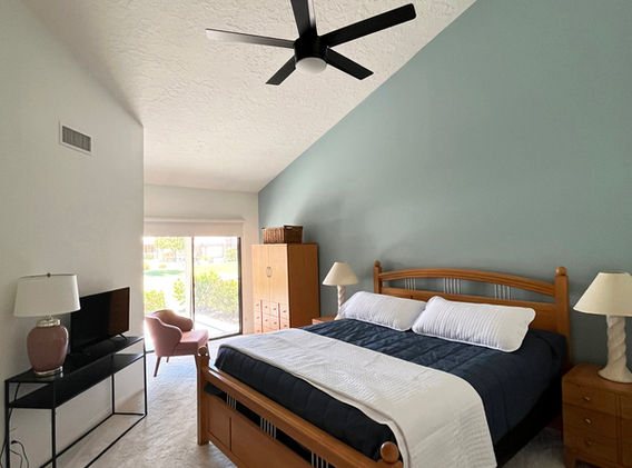 Spacious master bedroom with high vaulted ceiling, feature wall and sliding door to the patio