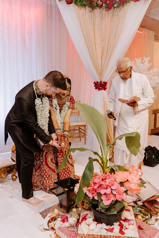 bride and groom with the pundit dropping rice into the holy fire
