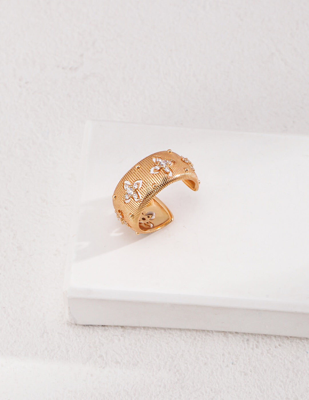 Gold crescent-shaped ring on white surface, minimalist jewelry design.