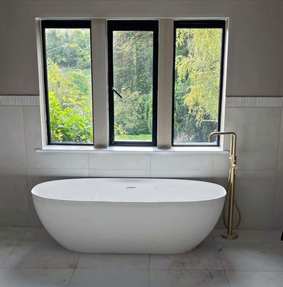Luxury freestanding bath on large marble floor tiles in a large bathroom