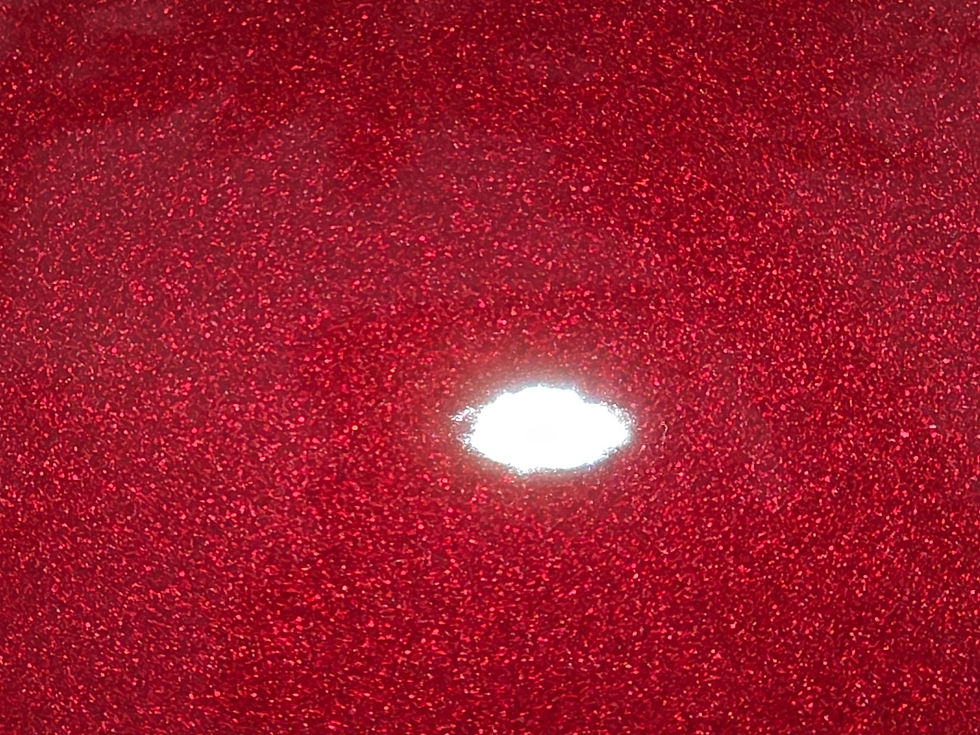 Close-up of a red glittery surface with a bright white light reflection in the center