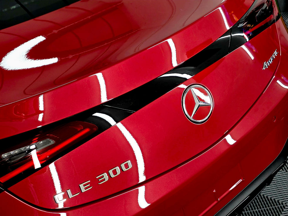 Close-up of a glossy red Mercedes CLE 300 rear with chrome badge and star emblem under bright lights