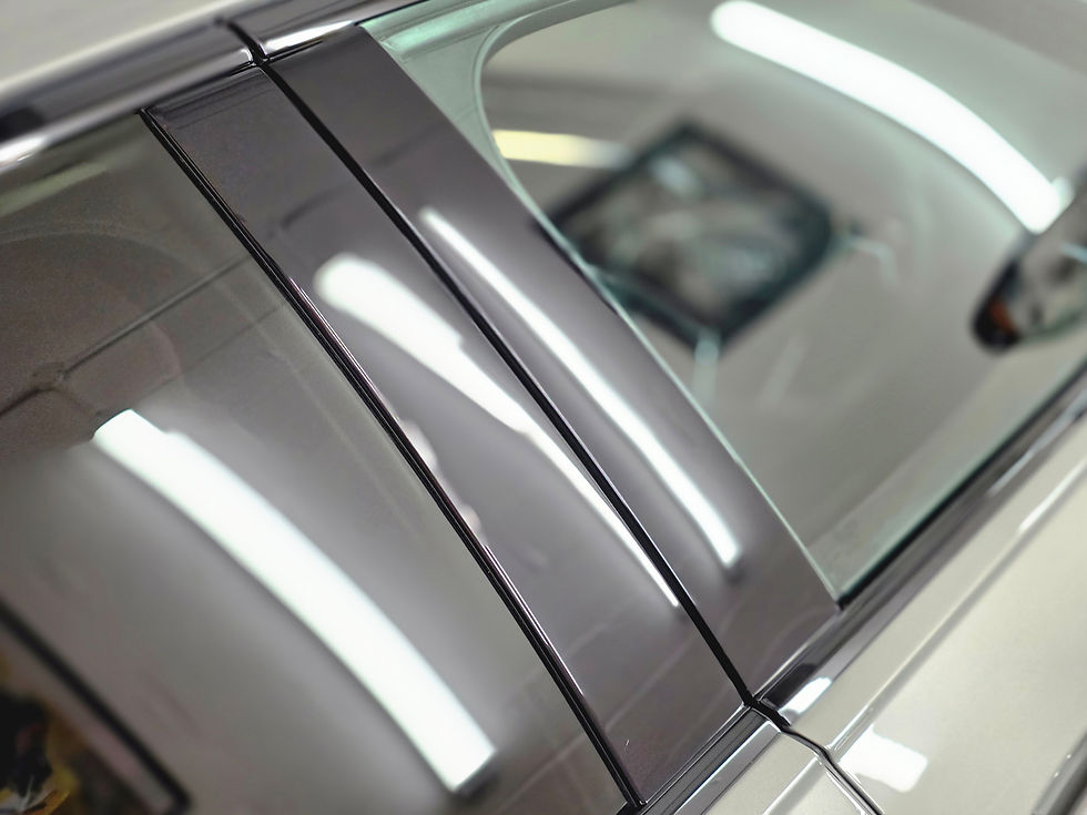Close-up of a car window with reflective tint, showing elongated reflections of overhead lights in a garage setting.