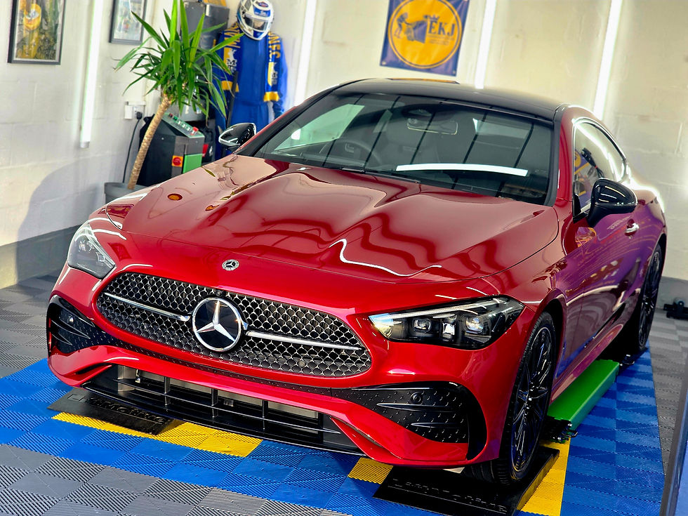 Red Mercedes coupe in a showroom, with a blue-and-yellow racing suit mannequin, EKJ banner, and bright floor tiles.