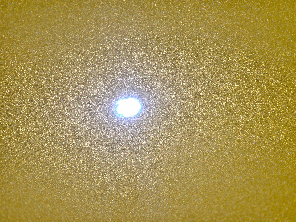 Bright light on a textured, golden surface creating a sparkling effect. The mood is warm and reflective. No text visible.