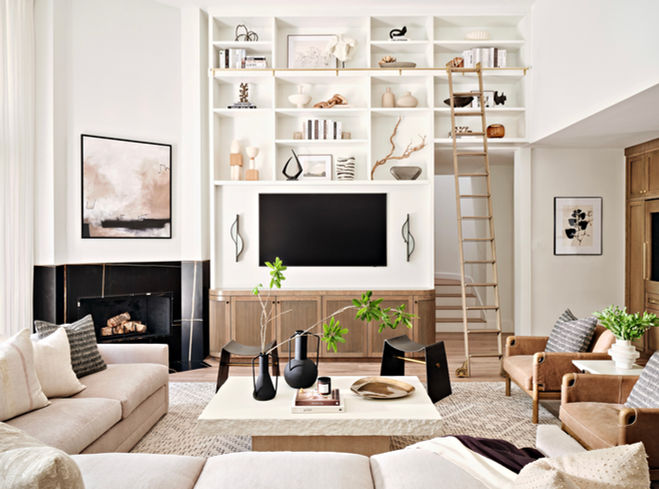 Living room with custom built-in shelving, media wall, sliding ladder, layered seating, and warm wood accents.